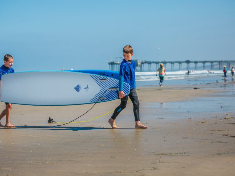 kids carrying surfboard at surf camp in la jolla shores for Surf Education Academy