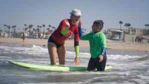 surf instructor at surf camp with camper excited in la jolla shores in san diego california