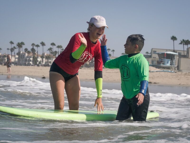 surf instructor at surf camp with camper excited in la jolla shores in san diego california
