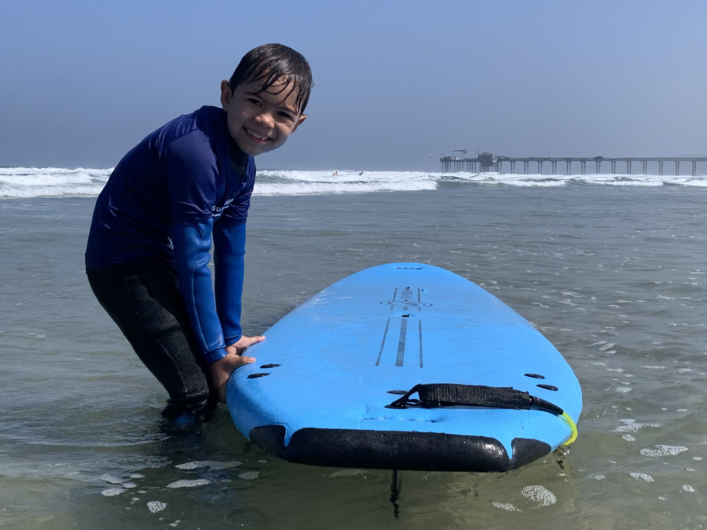 surf edcuation academy with a rental board soft top foam surfboard with a young kid renter