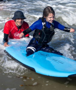 Sean Brody with Surf Education Academy is helping an adaptive surfer with CAF staff  at L a Jolla Shores Beach in San Diego