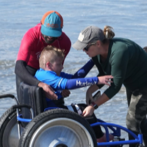 Sean Brody with Surf Education Academy is helping an adaptive surfer with CAF staff  at L a Jolla Shores Beach in San Diego